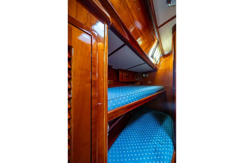 Ghost Yacht Photos Pics Interior of 2000 Hinckley Sou'wester Stoway Sloop with wooden bunk beds and blue cushions.