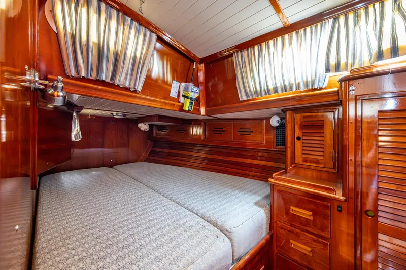 Ghost Yacht Photos Pics Luxurious wooden cabin interior of 2000 Hinckley Sou'wester Stoway Sloop with cozy bed and striped curtains.