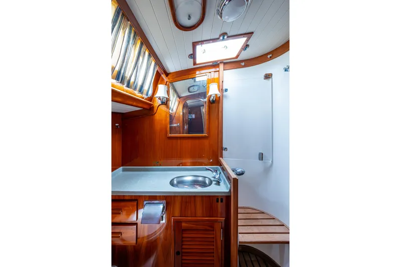 Ghost Yacht Photos Pics Hinckley Sou'wester Stoway Sloop 2000 bathroom with wooden cabinetry and modern fixtures.