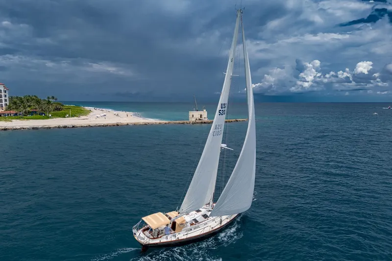 Ghost Yacht Photos Pics Hinckley Sou'wester Stoway Sloop sailing near a beach under a cloudy sky, 2000 model.