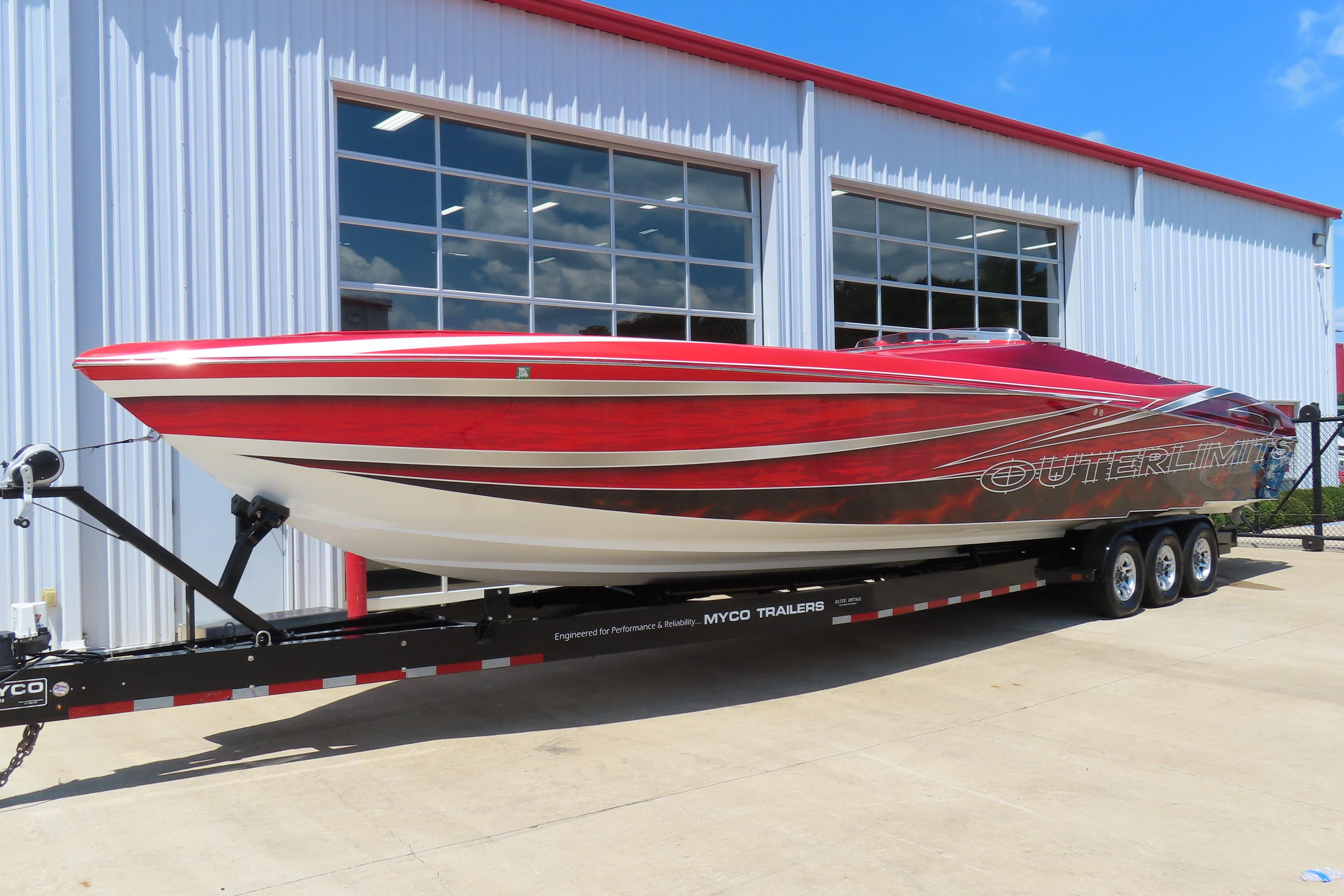 2004 Outerlimits 42 Legacy speedboat on trailer, parked outside a modern building.