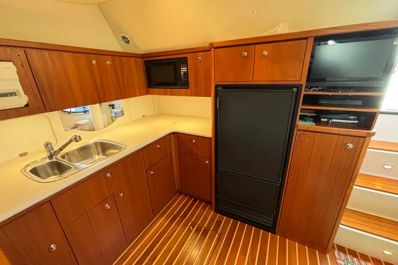  Yacht Photos Pics 2002 Tiara Yachts 4100 Open galley with wood cabinetry, sink, fridge, and microwave.