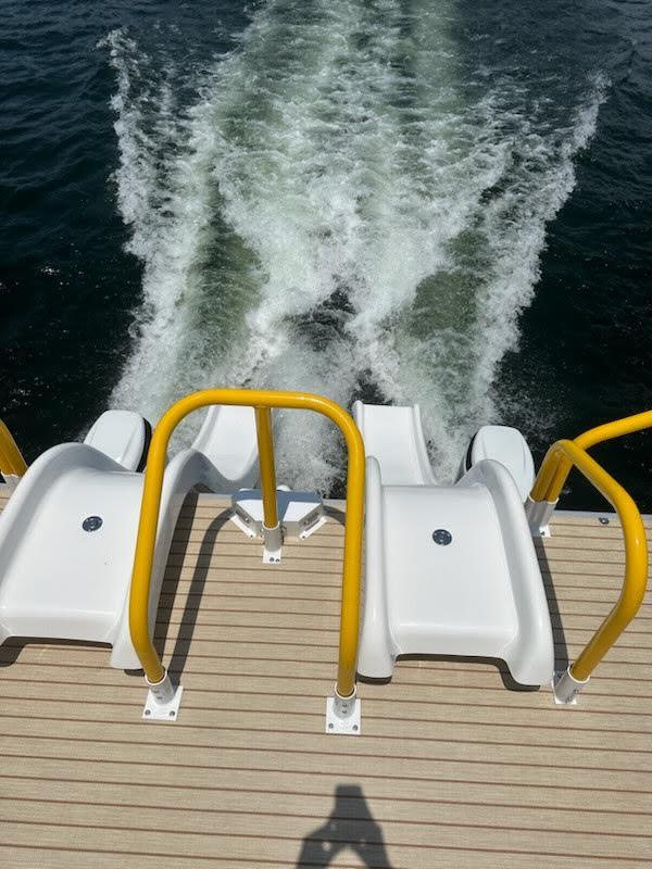Aloha Pontoon 40' Sky View 2025 with water slides and yellow railings on a lake.