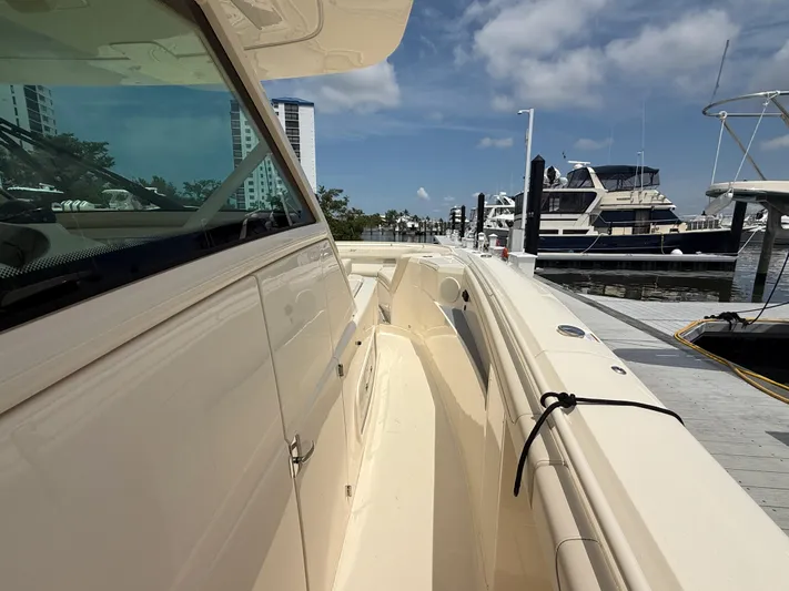  Yacht Photos Pics 2025 Scout 400 LXF boat docked at marina, clear sky, luxury yachts in background.