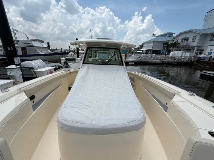  Yacht Photos Pics 2025 Scout 400 LXF boat docked, featuring a covered seating area under a cloudy sky.
