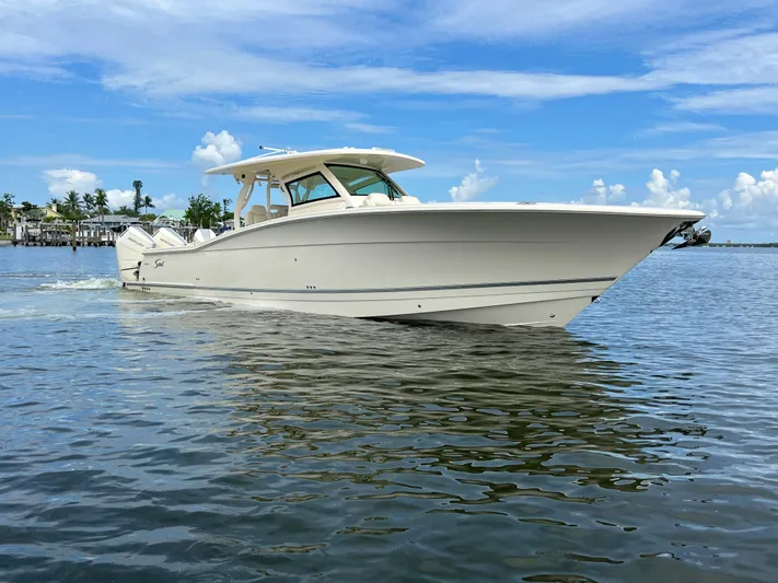  Yacht Photos Pics 2025 Scout 400 LXF boat cruising on calm water under a clear blue sky.