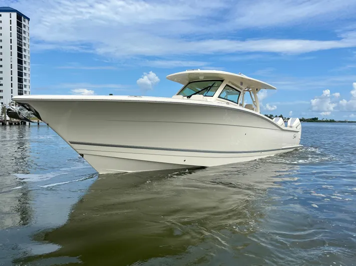  Yacht Photos Pics 2025 Scout 400 LXF boat cruising on calm water near a tall building.
