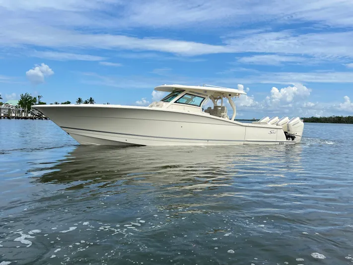  Yacht Photos Pics 2025 Scout 400 LXF boat cruising on calm water under a clear blue sky.