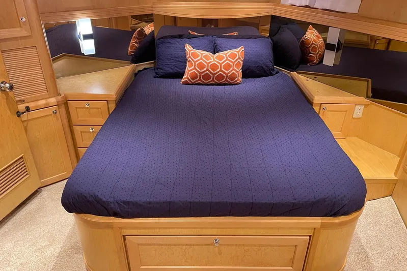 Aventis Yacht Photos Pics Luxurious bedroom interior of 1999 McKinna 57 Pilothouse yacht with navy bedding and orange accents.