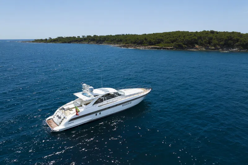  Yacht Photos Pics 2006 Mangusta 80 yacht cruising near a lush, green coastline.