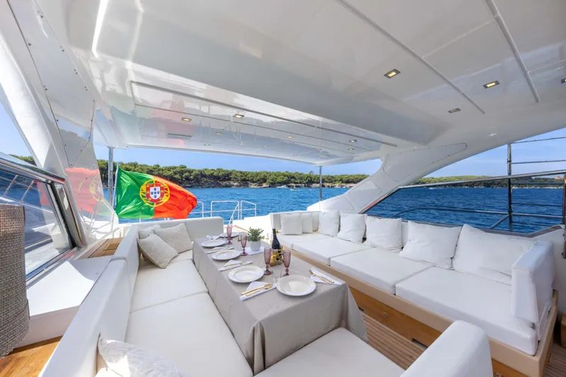  Yacht Photos Pics Luxurious 2006 Mangusta 80 yacht deck with elegant seating, dining setup, and Portuguese flag.