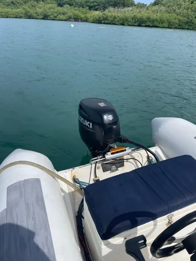  Yacht Photos Pics 2005 Lagoon 570 Switch boat with Suzuki outboard motor on calm water.