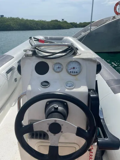  Yacht Photos Pics 2005 Lagoon 570 Switch boat helm with steering wheel and gauges, docked by lush greenery.