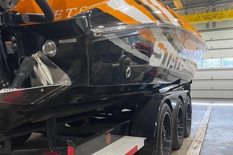 2019 Statement 350 boat on trailer in garage, featuring sleek black and orange design.
