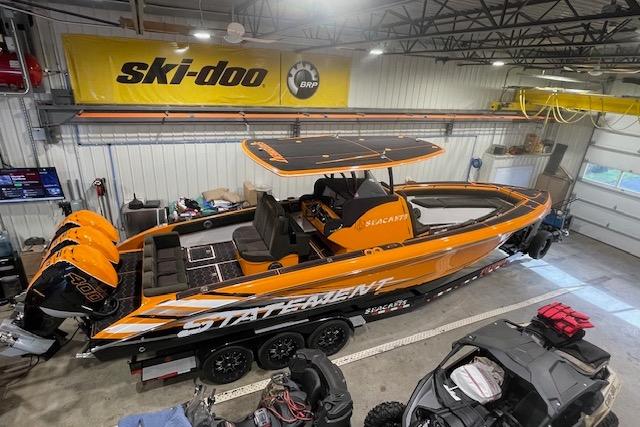 Orange 2019 Statement 350 boat with triple engines in a garage, under a Ski-Doo banner.