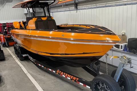 Orange 2019 Statement 350 boat on trailer in a garage setting.