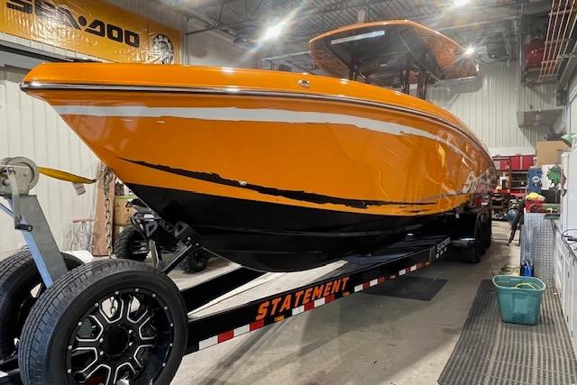 Orange 2019 Statement 350 boat on trailer in a garage setting.