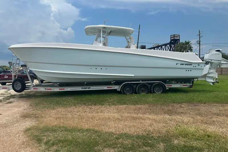 Cat Gone Willd Yacht Photos Pics 2023 Twin Vee 340 GFX CC boat on trailer, parked on grass under cloudy sky.