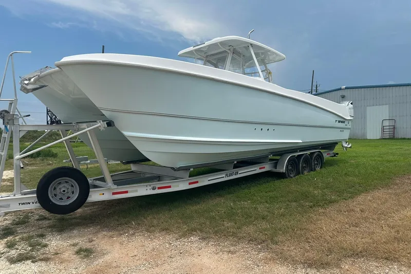 Cat Gone Willd Yacht Photos Pics 2023 Twin Vee 340 GFX CC boat on trailer, parked on grass near a building.