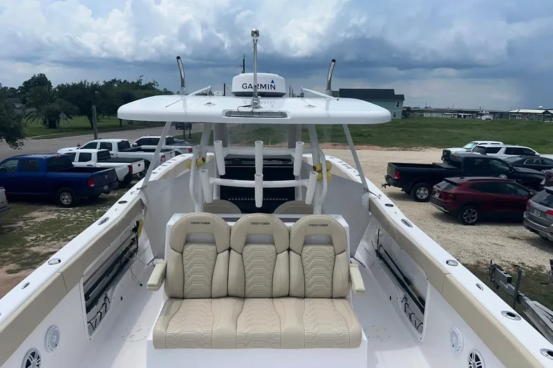 Cat Gone Willd Yacht Photos Pics 2023 Twin Vee 340 GFX CC boat with beige seating, parked near vehicles under cloudy sky.