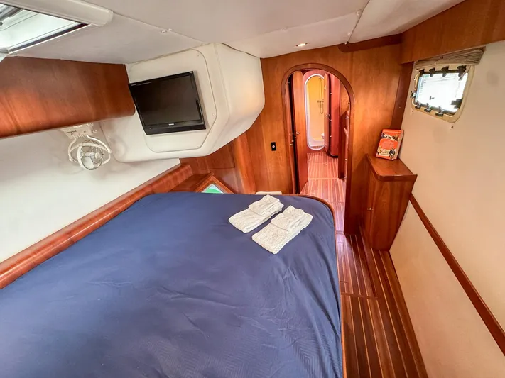 Adventure Yacht Photos Pics Cozy cabin interior of 2013 Antares 44i yacht with bed, TV, and wooden decor.