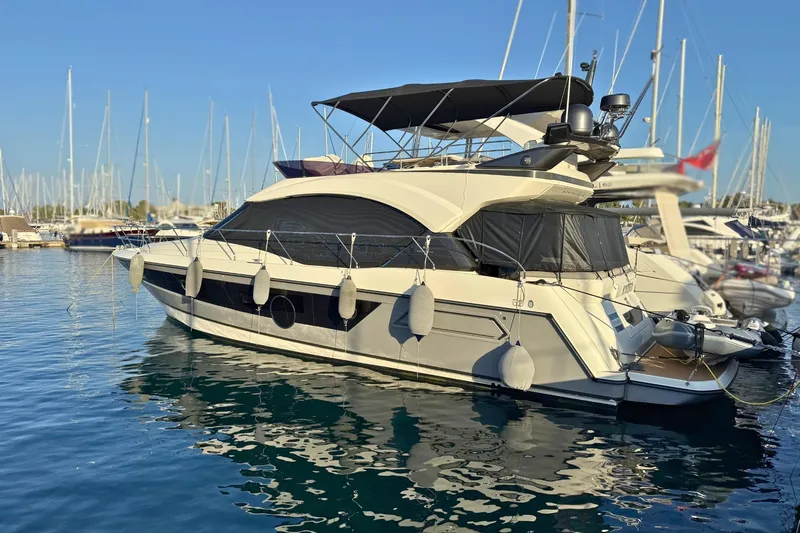  Yacht Photos Pics 2020 Beneteau Monte Carlo 52 yacht docked in marina, surrounded by other boats.
