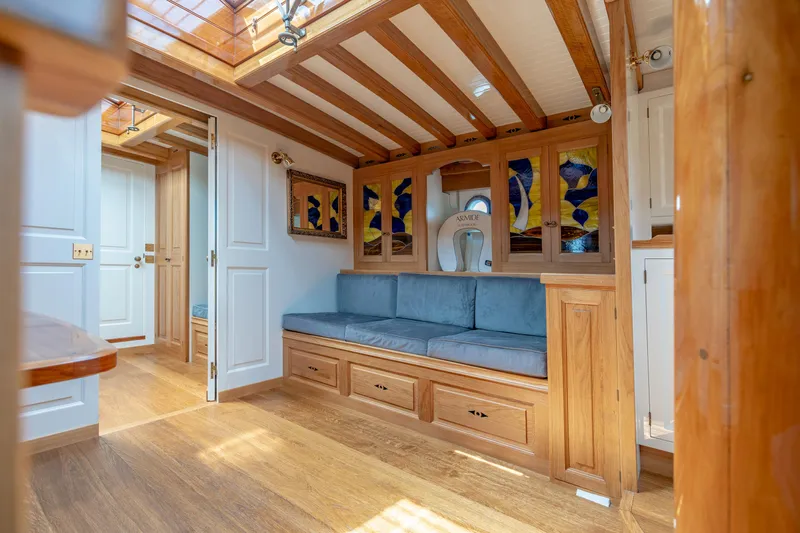 Armide Yacht Photos Pics 1938 Custom By Classic Works yacht interior with wooden beams, blue seating, and stained glass windows.