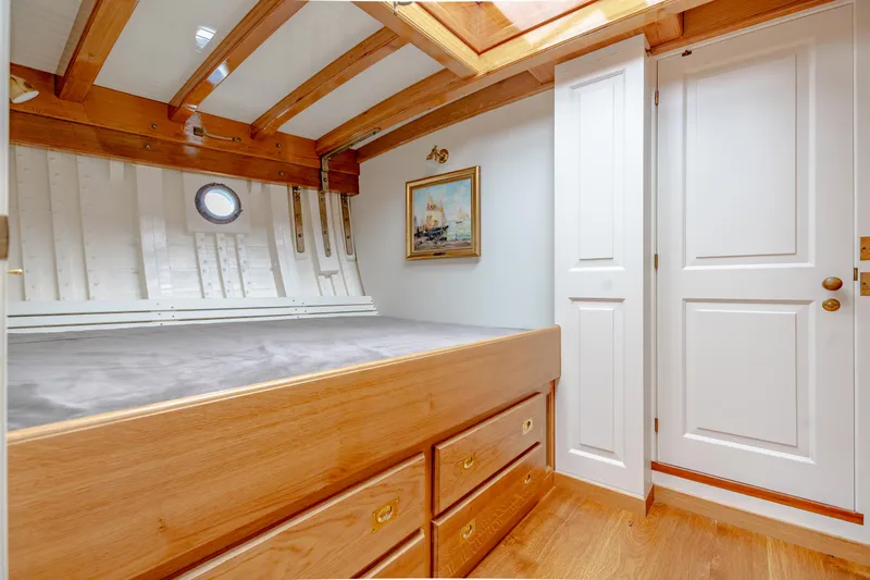 Armide Yacht Photos Pics 1938 Custom Classic Works boat cabin with wooden bed, drawers, and porthole window.