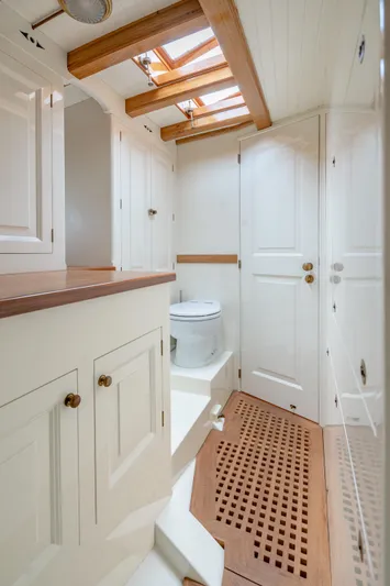 Armide Yacht Photos Pics 1938 Custom Classic Works yacht bathroom with skylight, wooden accents, and white cabinetry.