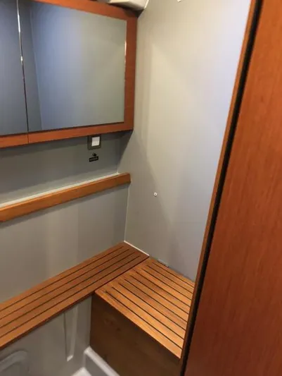 Cameli Yacht Photos Pics Interior of 2020 Beneteau Oceanis 55.1 yacht, featuring wooden seating and mirrored cabinet.