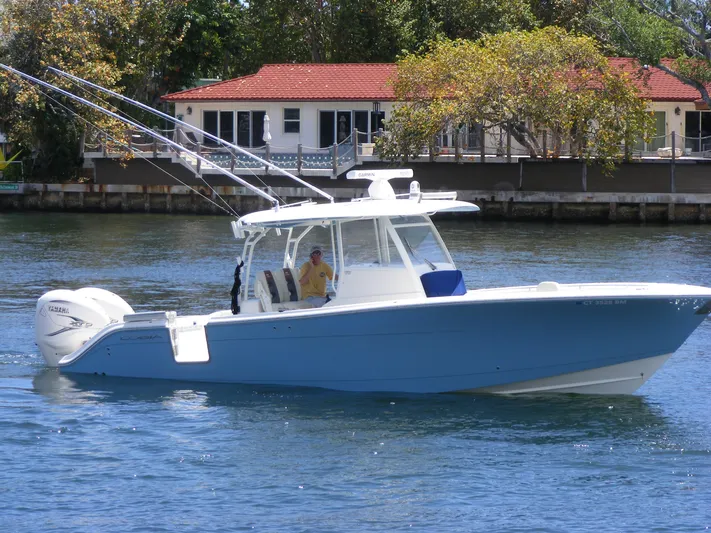  Yacht Photos Pics 2020 Cobia 350 Center Console boat on water near a house with red roof.