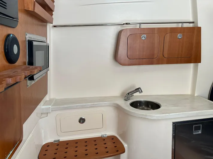  Yacht Photos Pics 2023 Grady-White Canyon 376 boat interior with kitchenette, sink, and wooden cabinets.