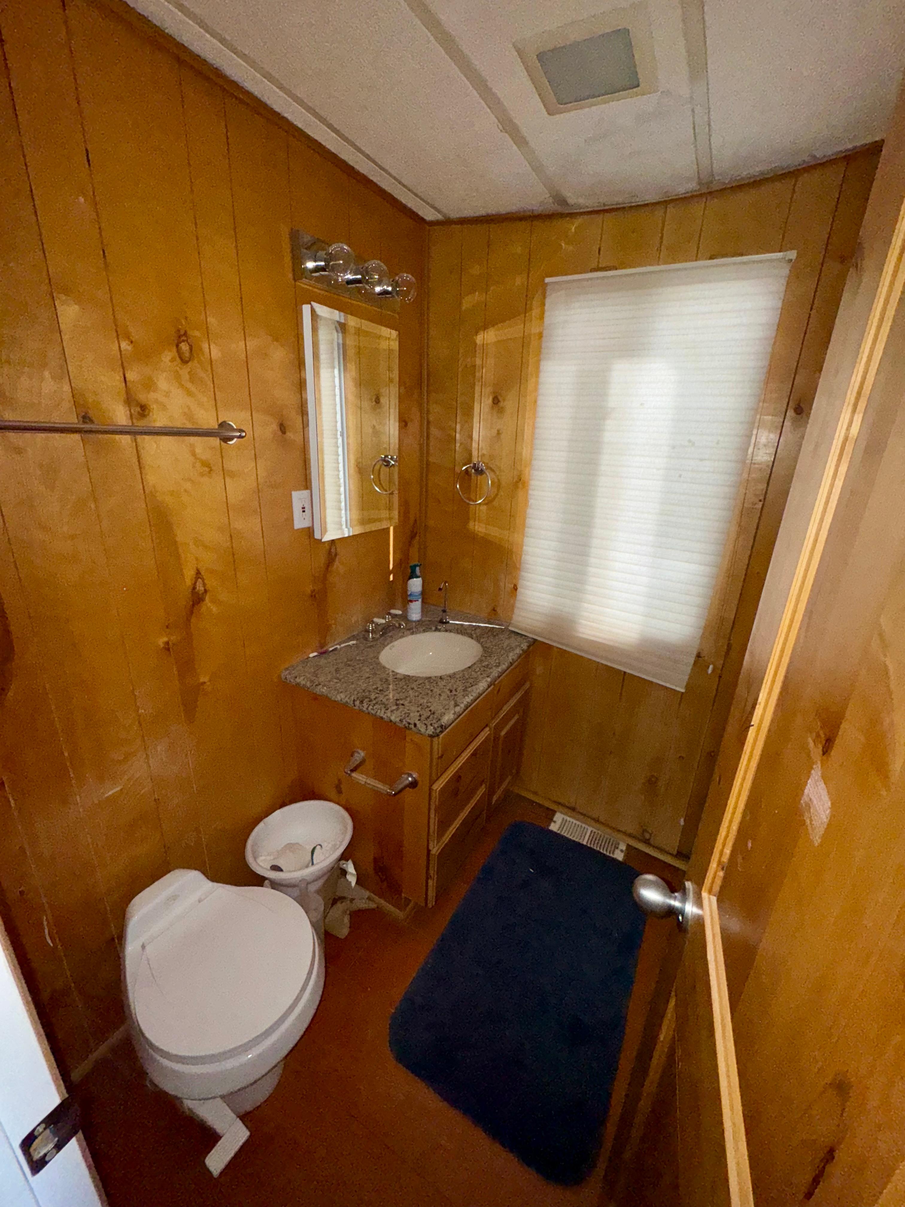 Wood-paneled bathroom with granite countertop, toilet, and window. Lakeview Full Ownership, 1993 model.