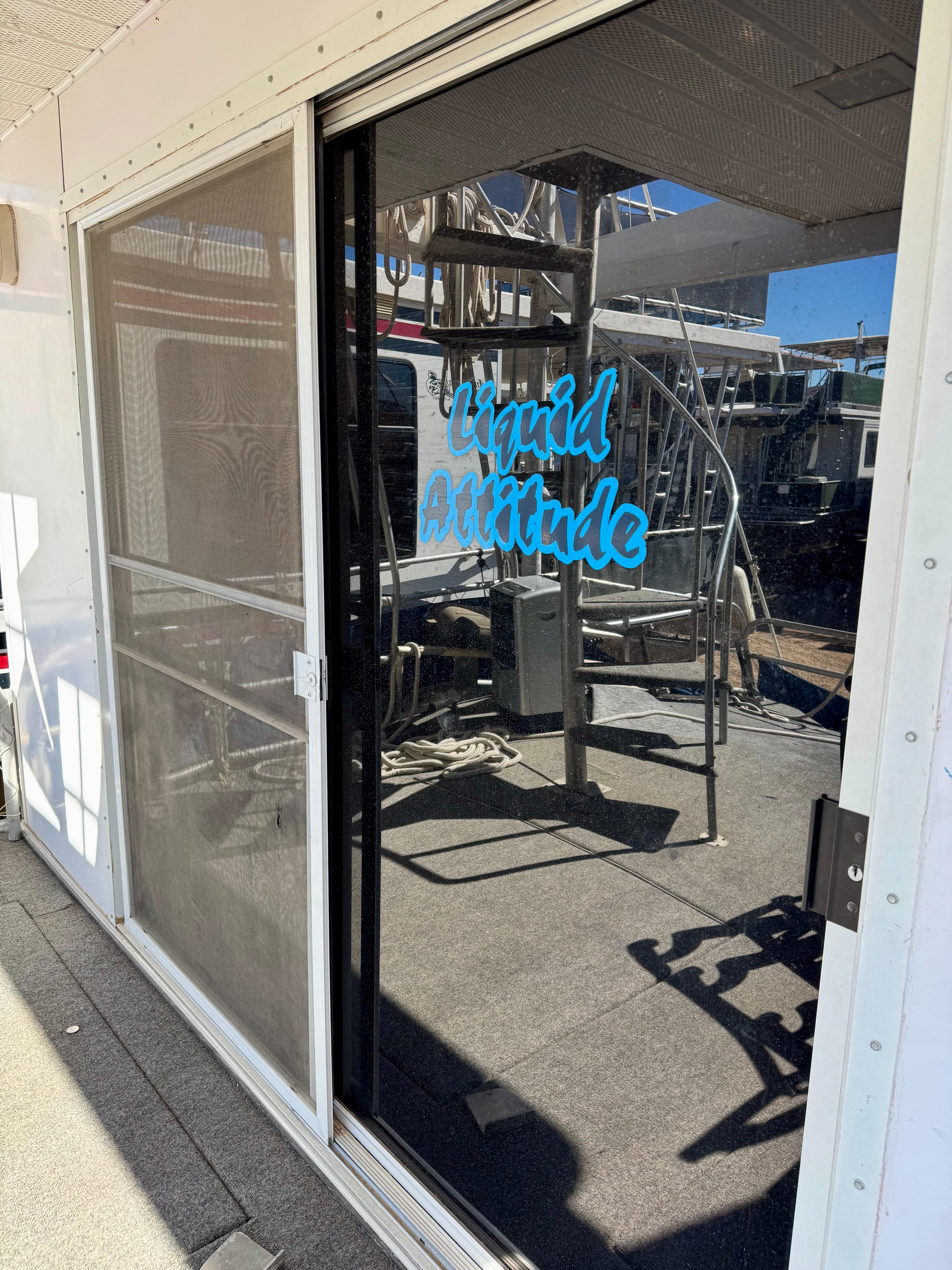 Sliding glass door with "Liquid Attitude" text on a 1993 Lakeview Full Ownership boat.