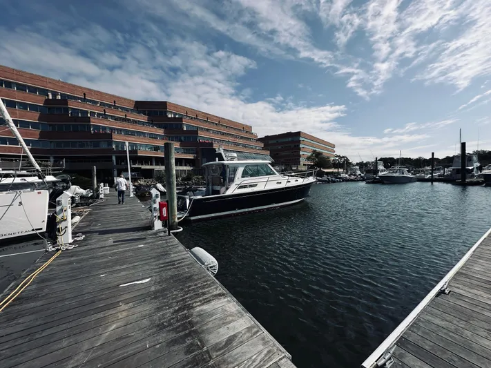 Someday Yacht Photos Pics Back Cove 34 yacht docked at marina, 2012 model, with modern buildings in the background.