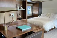 Luxurious yacht interior with wooden desk, modern decor, and cozy bed, Custom Line 100, 2015 model.
