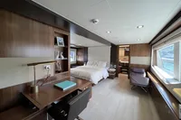 Luxurious yacht interior with modern design, featuring a bedroom, desk, and seating area. Custom Line 100, 2015.