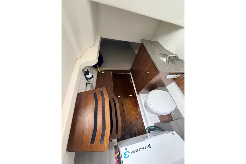  Yacht Photos Pics 2019 Wellcraft 352 Fisherman cabin interior with sink, toilet, and wooden flooring.