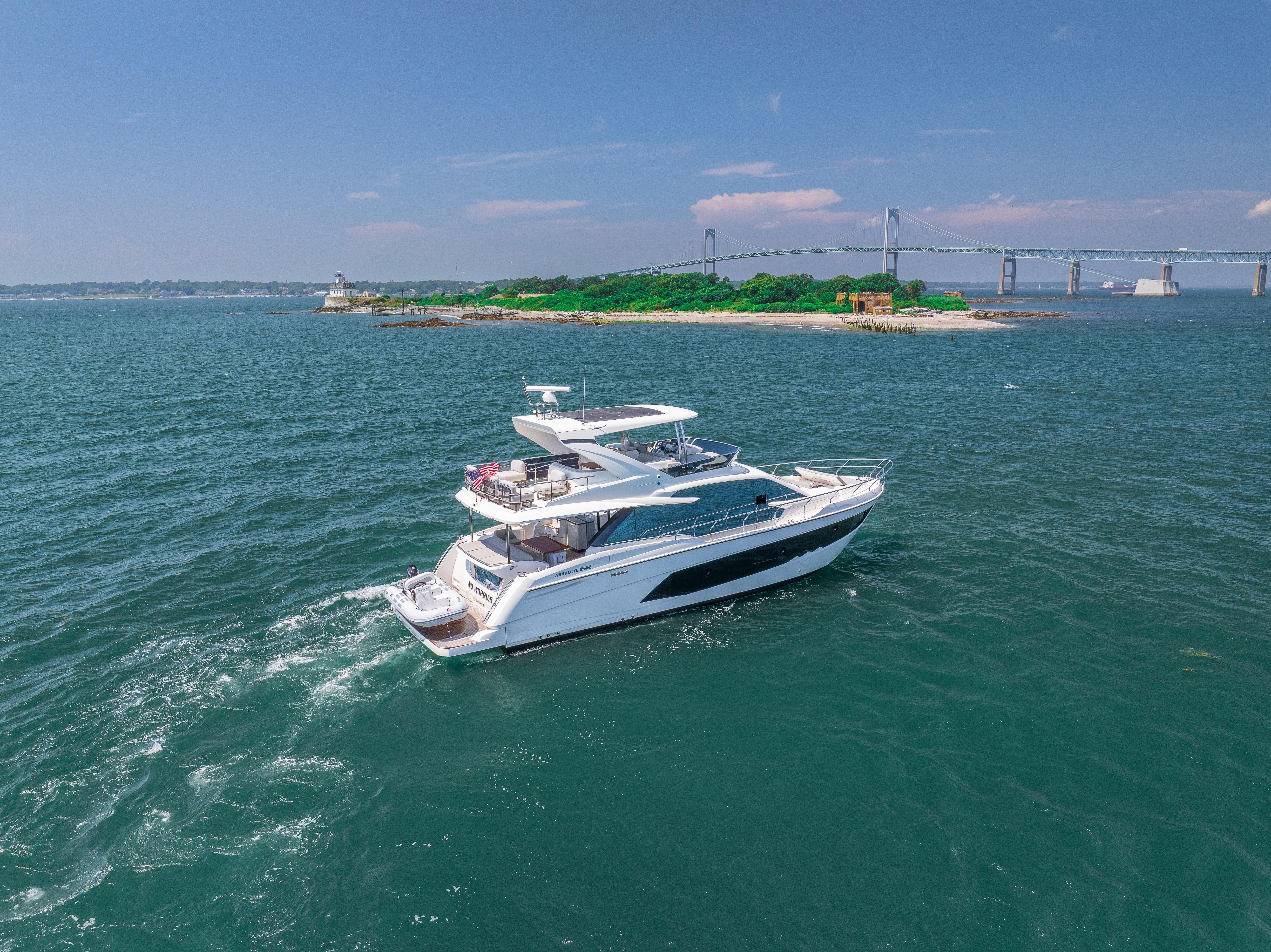 2023 Absolute 62 Fly yacht cruising near a scenic island and bridge.