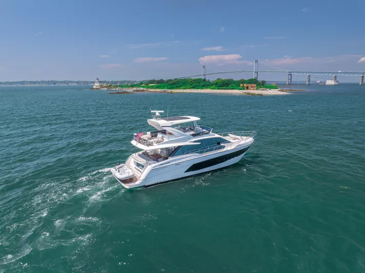  Yacht Photos Pics 2023 Absolute 62 Fly yacht cruising near a scenic island and bridge.