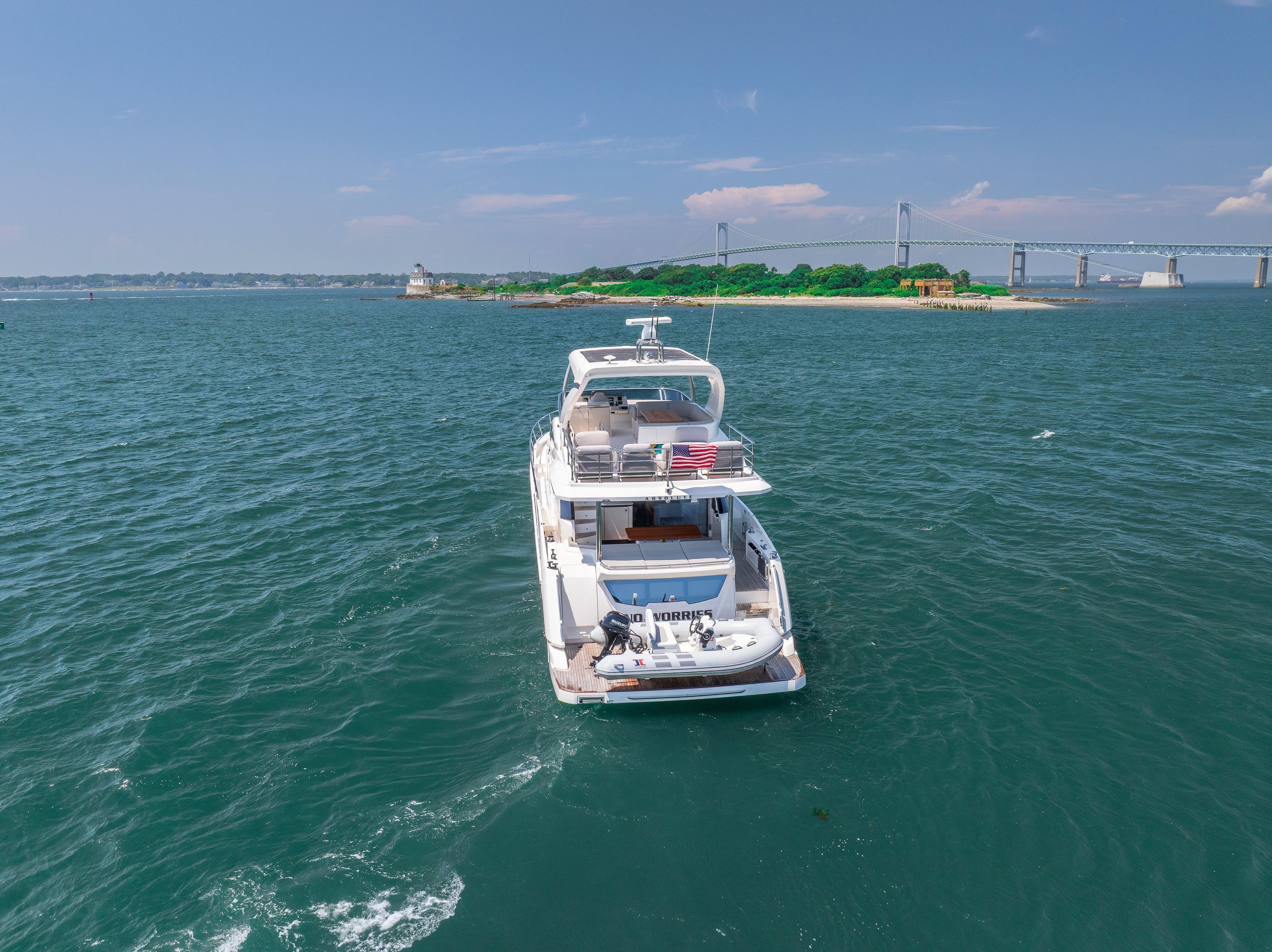 Luxury yacht Absolute 62 Fly 2023 cruising near scenic coastline and bridge.