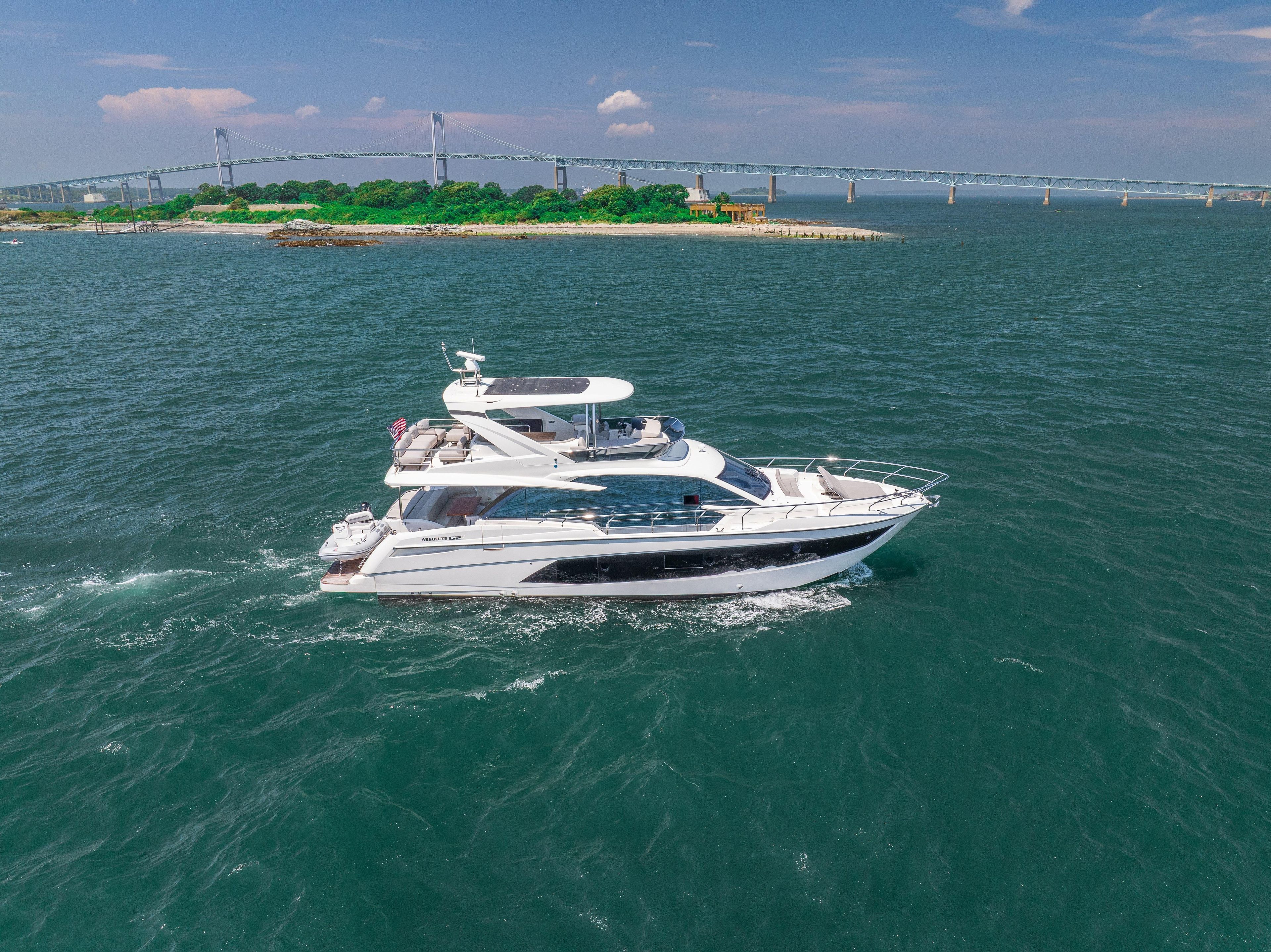 2023 Absolute 62 Fly yacht cruising near a bridge on a sunny day.
