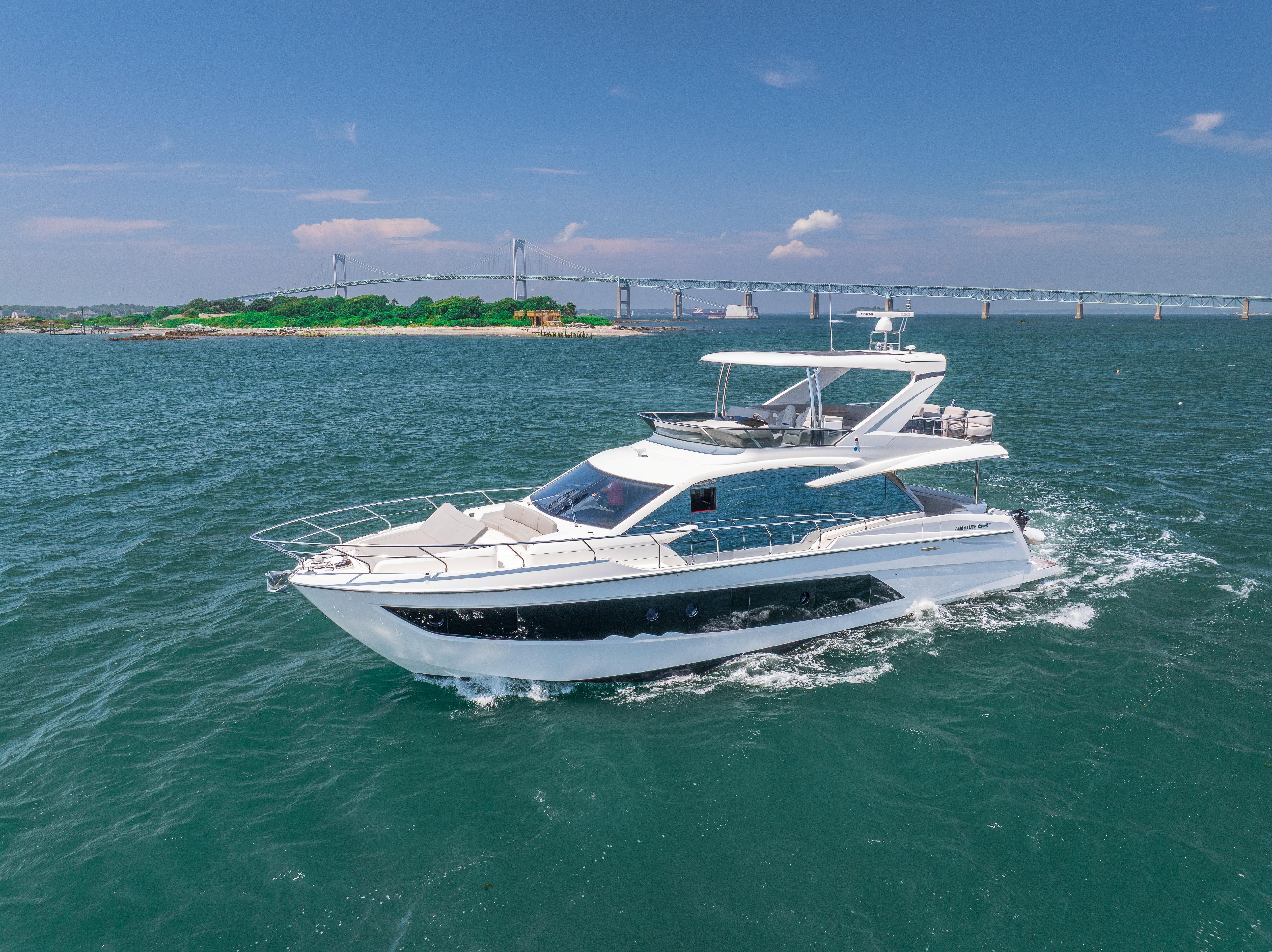 2023 Absolute 62 Fly yacht cruising on open water with a scenic bridge backdrop.