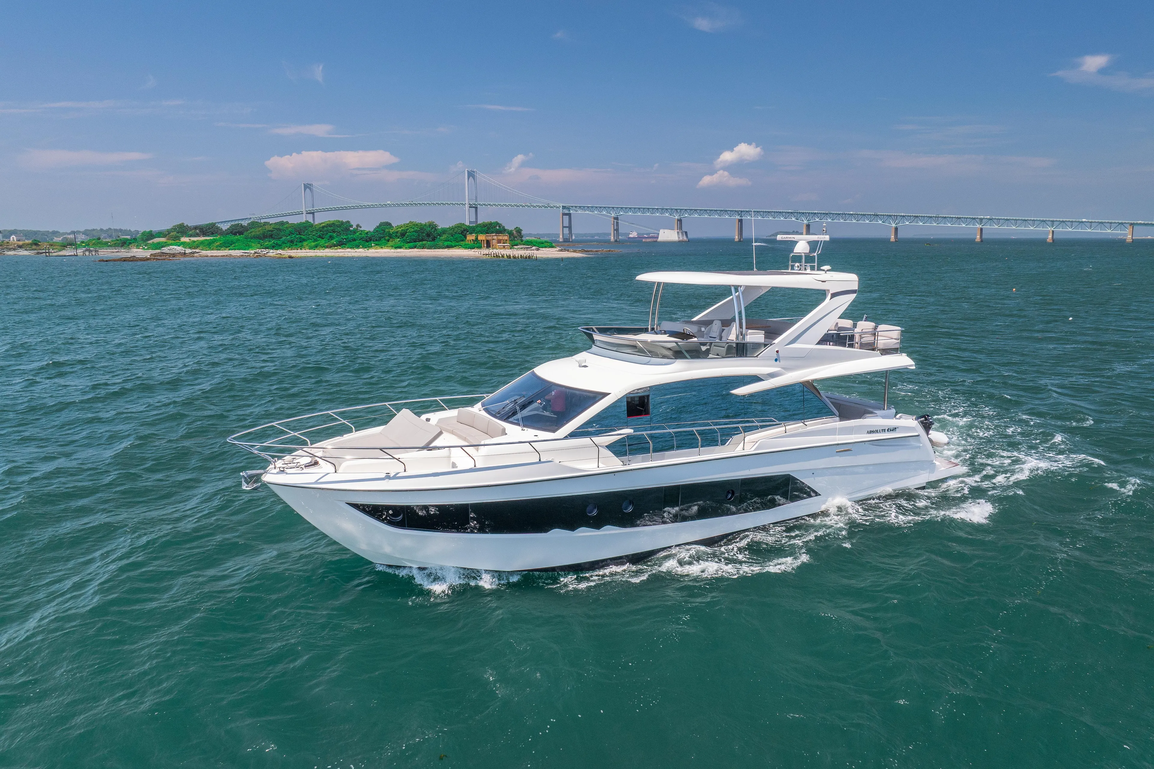 2023 Absolute 62 Fly yacht cruising on open water with a scenic bridge backdrop.