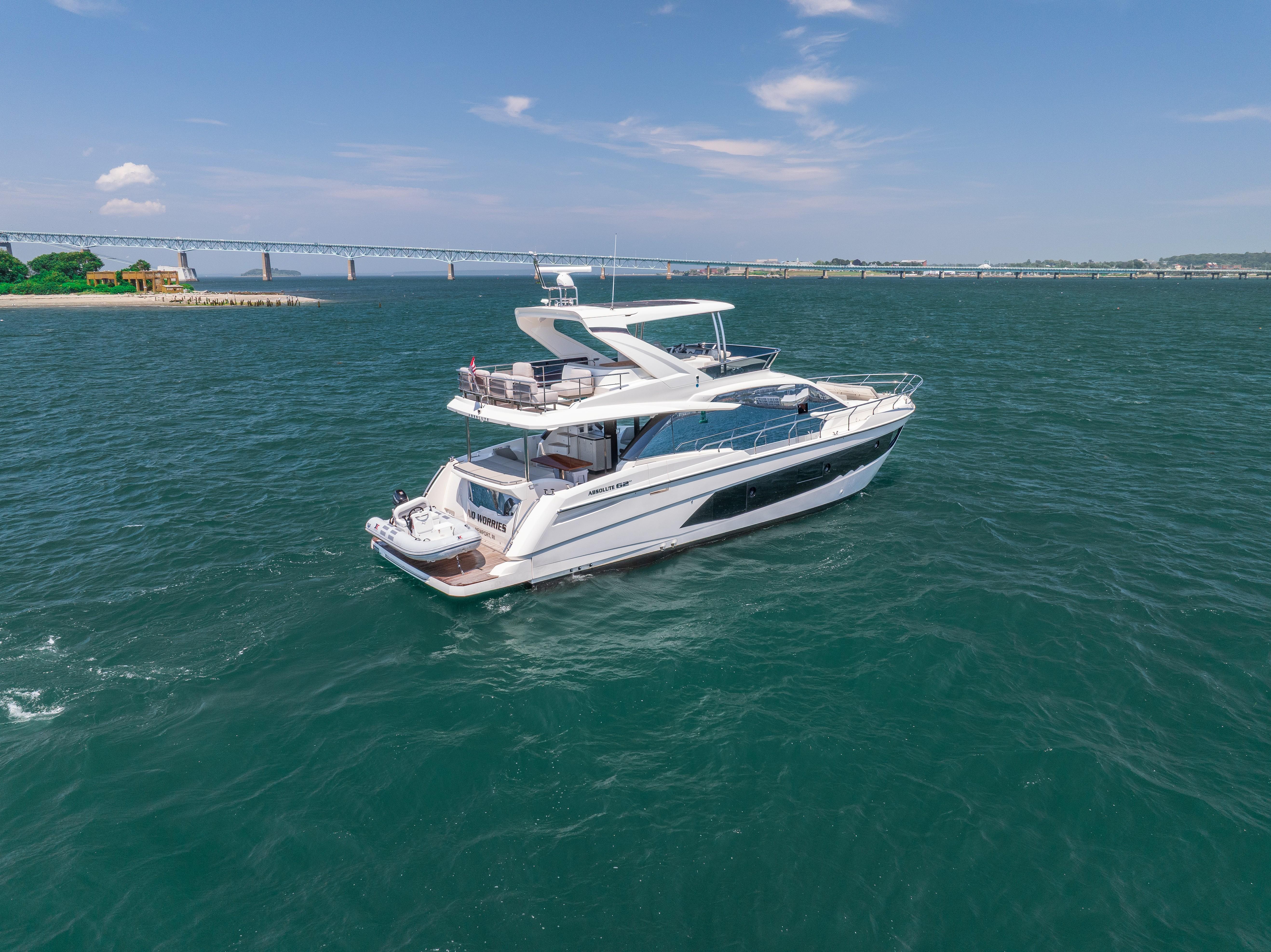 2023 Absolute 62 Fly yacht cruising on open water near a bridge.
