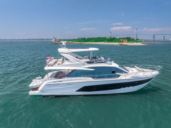  Yacht Photos Pics 2023 Absolute 62 Fly yacht cruising near a scenic island and bridge.