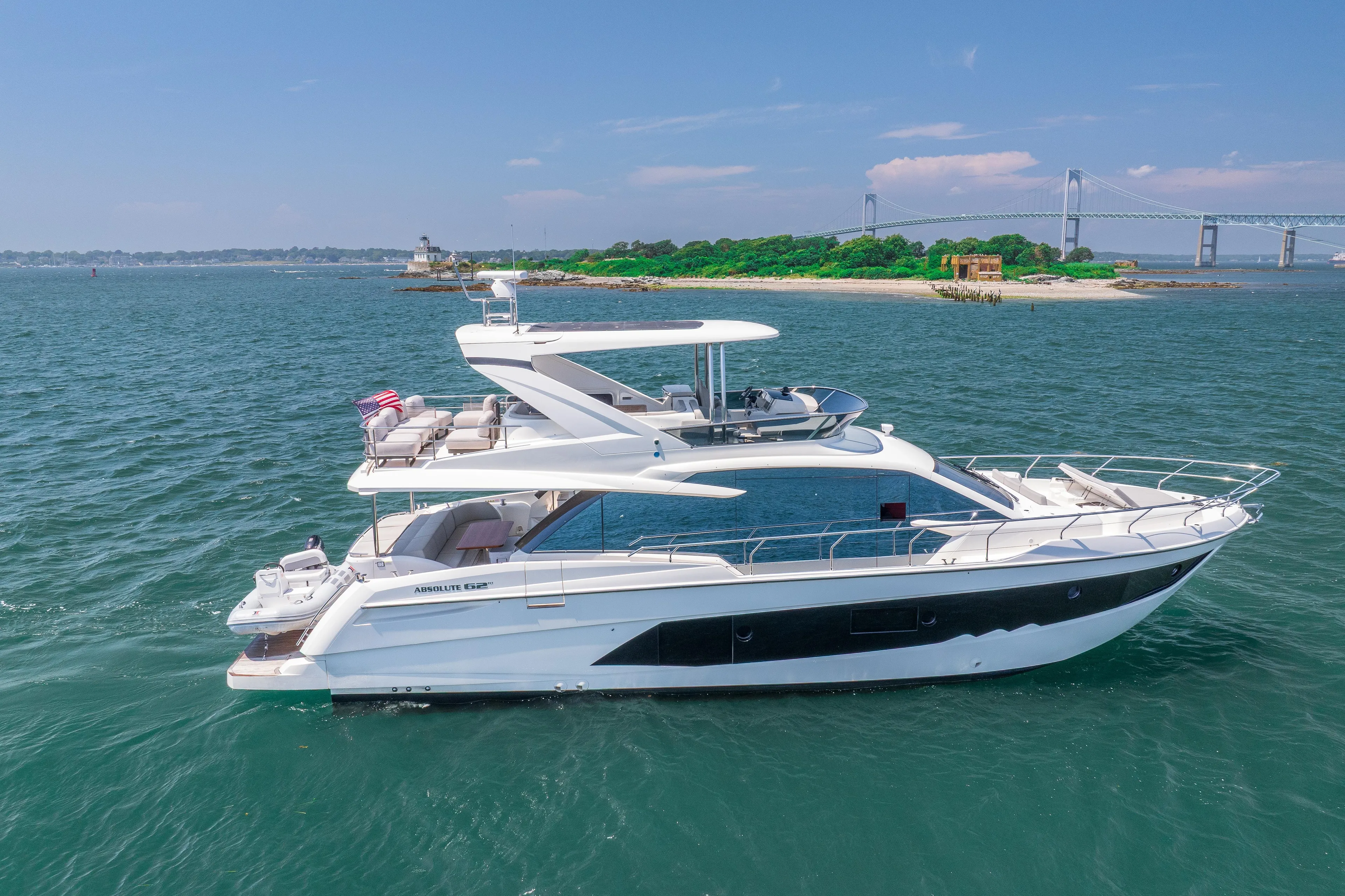 2023 Absolute 62 Fly yacht cruising near a scenic island and bridge.