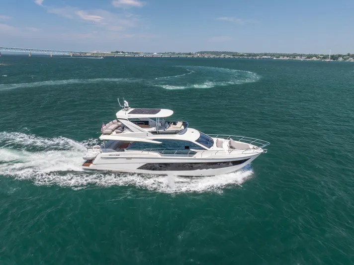  Yacht Photos Pics 2023 Absolute 62 Fly yacht cruising on open water, clear sky background.