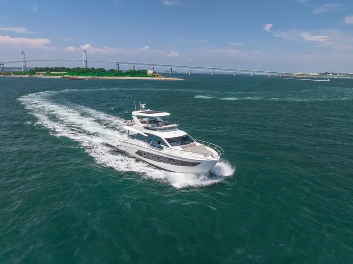  Yacht Photos Pics 2023 Absolute 62 Fly yacht cruising on open water near a bridge.
