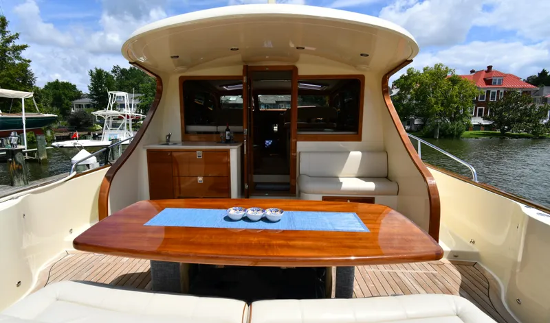 Mack Yacht Photos Pics 2020 Palm Beach Motor Yachts PB52, elegant deck with wooden table and seating, docked by the water.